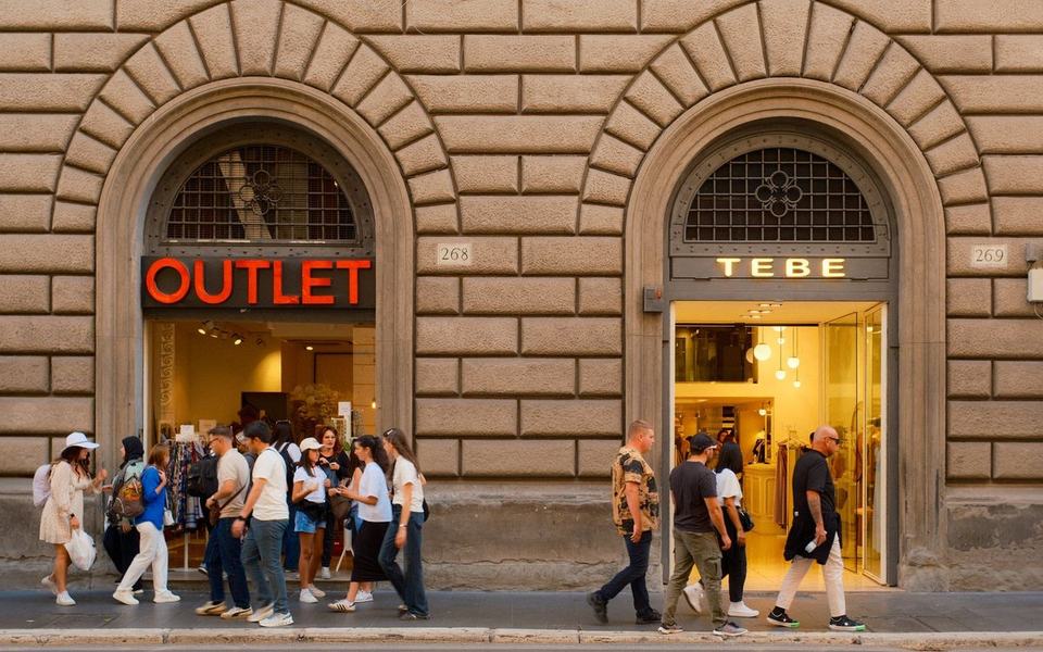 Group of shoppers walking past and into arched shop entrances on a street