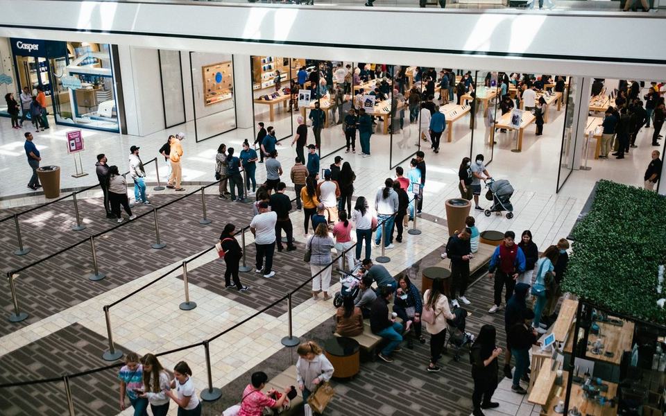 High-angle view of a long queue of people behind stanchion ropes in a mall outsi